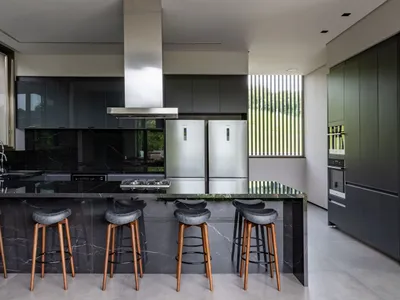 Modern kitchen featuring minimalist design, black marble countertops, and stainless steel appliances.