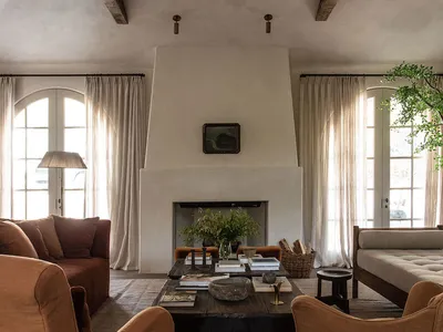 A rustic, industrial-style living room with concrete walls, wooden beams, and fabric seating.