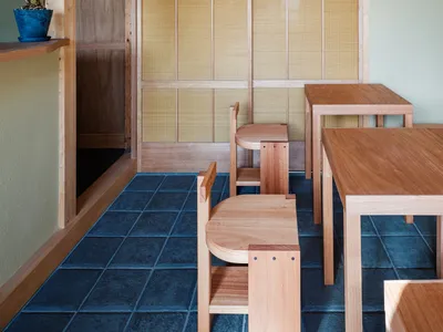 A modern restaurant interior with wooden furniture and plants on shelves.