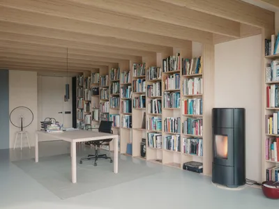 A modern home office featuring wooden walls and bookshelves filled with books.