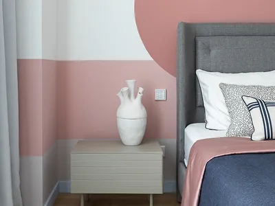 Modern bedroom featuring a gray upholstered bed, a blue and pink bedding set, a gray side table with a white ceramic vase, an