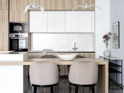 Modern kitchen with marble countertops and white wooden cabinets and table.
