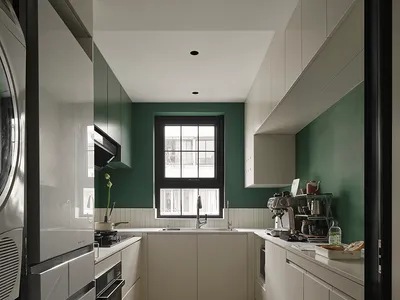 A modern minimalist kitchen with white cabinets, a large window, and green accents.