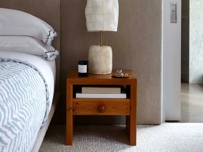 Minimalist bedroom with a wooden bedside table featuring a paper lamp.