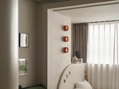 A modern bedroom featuring a bed with a fabric headboard and a glass coffee table with books and a candle.