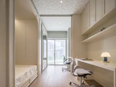 A modern minimalist office and bedroom with white furnishings and patterned ceiling.