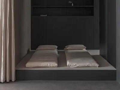A minimalist bedroom with black wooden furniture and beige bedding.