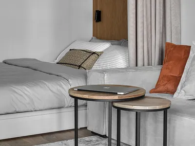 A minimalist bedroom featuring a grey bed with white and brown pillows, and a coffee table.