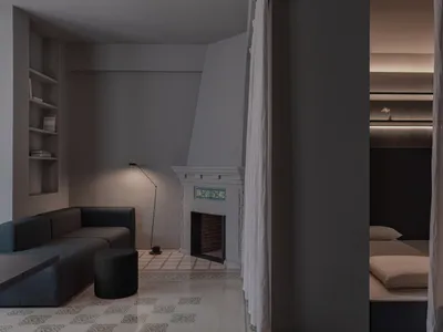 A minimalist bedroom featuring a plaster floor, a bed with beige bedding, and curtains leading to a separate sleeping area wi