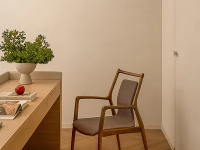 Modern home office featuring a wooden desk and chair with a potted plant and books on the desk.
