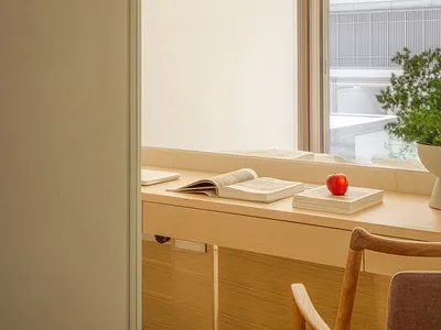 A minimalist home office setup featuring a wooden desk with books and an apple.