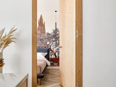 Modern minimalist bedroom featuring a wooden door and herringbone wood flooring.