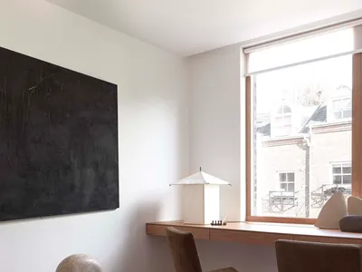 A modern home office featuring a sleek desk, stylish chairs, and a large window with a view of the outside.