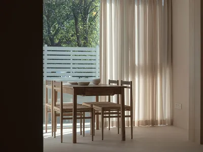 A living room with fabric curtains, wooden table, and chairs.