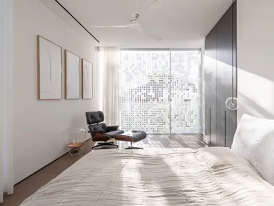A minimalist bedroom with a white bed and modern furniture.