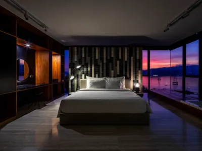 現代簡約臥室採用混凝土與大理石材質，並可欣賞水面上的日落景色。