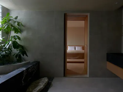A minimalist bedroom with grey walls, wooden floor, and bed.