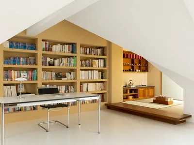 A modern home office with built-in bookshelves filled with books and a minimalist desk and chair.