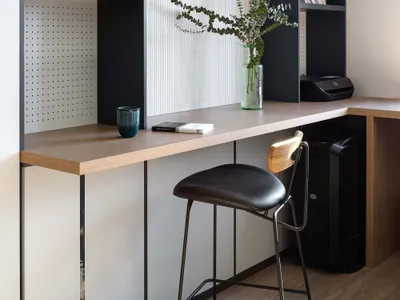 A modern home office space featuring a combination of wood and metal materials, including a desk with shelves, a chair, and d