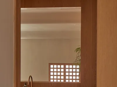A modern kitchen interior with wooden cabinets, a black countertop, and a window with a latticed frame.