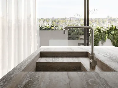 A modern kitchen with a marble countertop overlooks a serene outdoor garden.