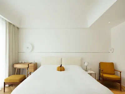 Minimalist bedroom with a yellow pumpkin on the bed.