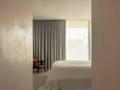 簡約臥室內擺放白色床鋪，窗戶上掛著灰色窗簾。