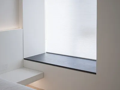 Minimalist bedroom featuring a floating shelf against a white wall.