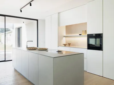 Minimalist kitchen with concrete island and white cabinets.