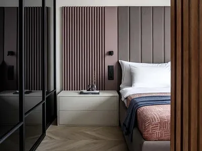 A minimalist bedroom featuring a upholstered bed frame, wood flooring, and metal accents.