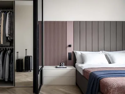 A minimalist bedroom with a gray upholstered headboard and a walk-in closet.