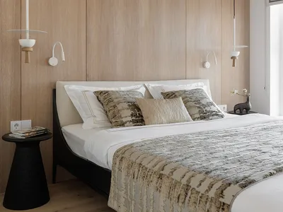 Modern minimalist bedroom with wooden walls and fabric bedding and pillows, featuring unique pendant lights and a low-profile