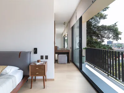 A modern, minimalist bedroom with wooden furniture and large windows overlooking greenery.