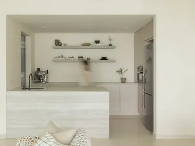 Modern, minimalist kitchen with concrete countertops and shelves.