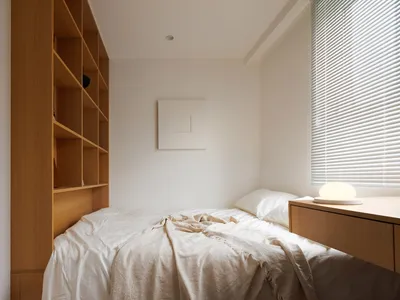 A minimalist bedroom with a bed, nightstand, and wooden shelves.