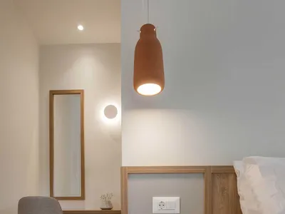 A minimalist bedroom featuring wood walls, a concrete floor, and a metal headboard.
