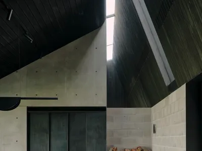 A spacious industrial-style living room featuring a concrete fireplace and numerous stacked logs.