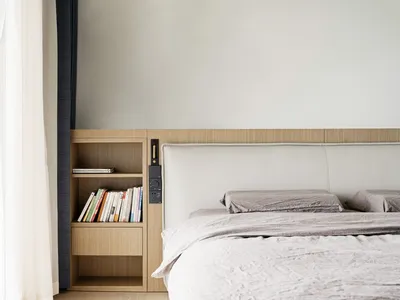 A minimalist bedroom featuring a wooden bookshelf with a bookcase and a modern bed with a cushioned headboard.