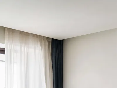 Minimalist bedroom featuring a large bed with white curtains and wooden walls.