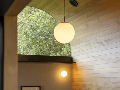 A minimalist bedroom featuring wooden walls and a green bedspread.