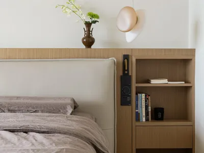 Modern, minimalist bedroom featuring wooden furniture and a vase with orchids.