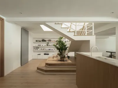 現代室內設計，呈現客廳結合廚房區域與樓梯，採用木質與白色素材。