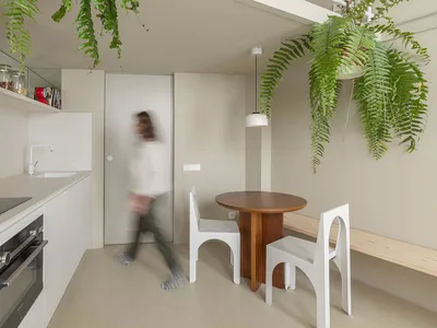 一間現代廚房採用白色極簡設計，搭配木質餐桌、白色餐椅與玻璃材質。