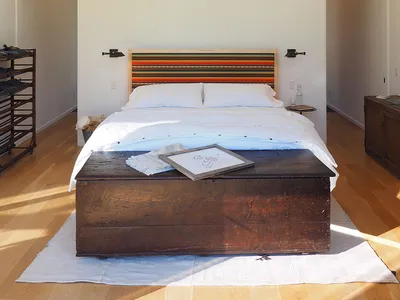 A minimalist bedroom featuring a wooden headboard and white linens on a large bed.
