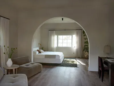 A minimalist bedroom with white furniture and soft lighting.