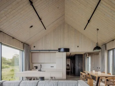 Modern, minimalist dining and kitchen area featuring wood finishes and open design.
