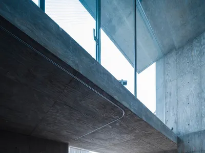 A modern bedroom with concrete walls and a wooden floor.
