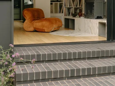 A cozy, industrial-style living room with a wooden floor, marble fireplace, and metal elements.