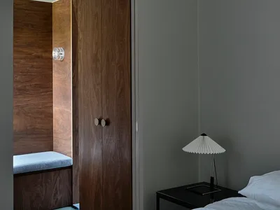 Minimalist bedroom featuring a dark wood cabinet and a bed with white linens.