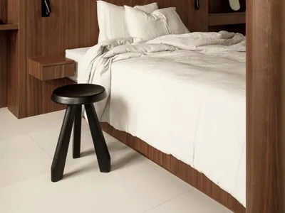 A minimalist bedroom with white bedding and wooden walls and floor.